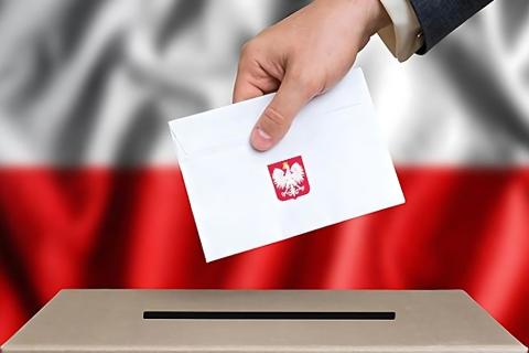 dłoń trzymająca kartkę z głosem nad urną wyborczą 