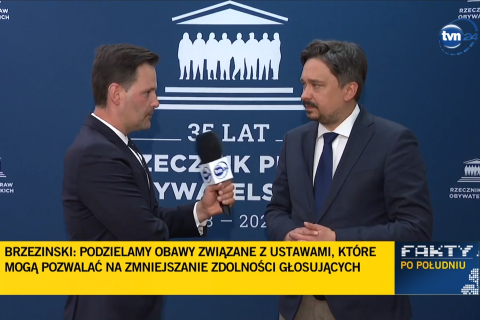 Zrzut ekranu programu telewizyjnego przedstawiający RPO Marcina Wiącka rozmawiającego z dziennikarzem na tle ścianki z napisem "Rzecznik Praw Obywatelskich"