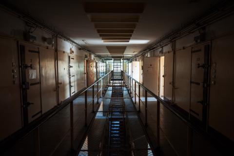 Ciemny korytarz więzienny z drzwiami do cel po obu stronach