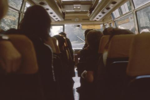 osoby siedzą w jadącym autobusie  