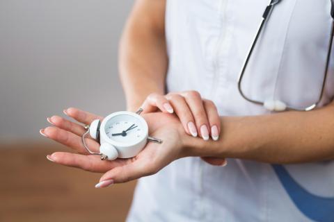 kobieta w ubiorze lekarskim trzyma w dłoni miernik czasu 