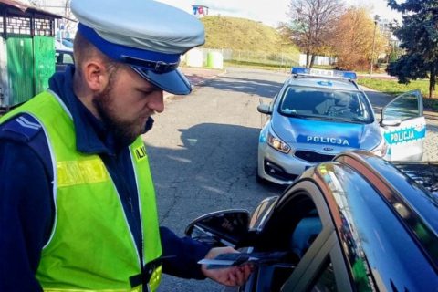 policjant  stoi nad samochodem podczas jego kontroli 