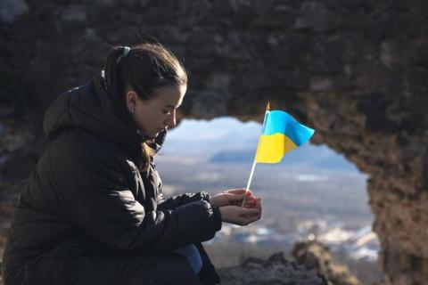 siedząca kobieta z małą flagą Ukrainy w dłoni