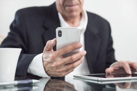 starszy mężczyzna trzyma telefon w ręce