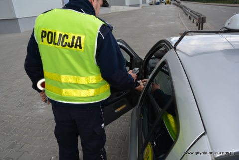 policjant stoi przy otwartych drzwiczkach auta 