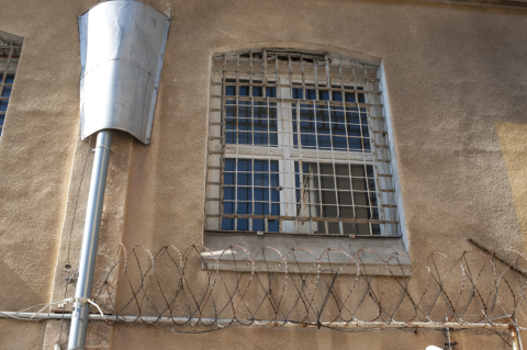 zakratowane okno w murze więzienia 