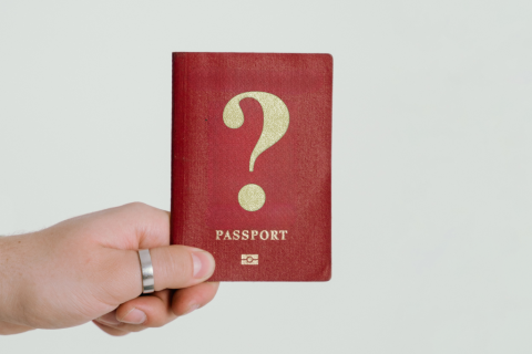 dłoń trzyma paszport ze znakiem zapytnia 