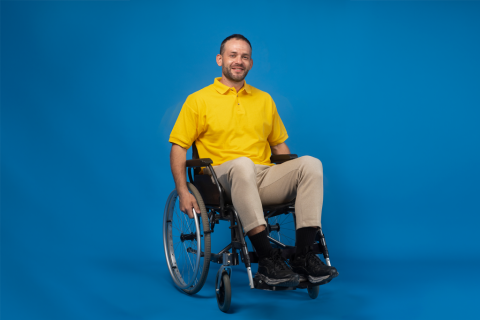 mężczyzna w żółtej koszulce na wózku na niebieskim tle