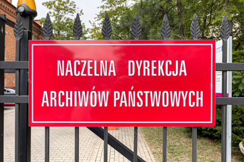 Na ogrodzeniu tablica z napisem Naczelna Dyrekcja Archiwów Państwowych 