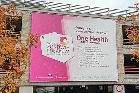 Duży banner nad wejściem do budynku, na bannerze kontury Polski i napis "Kongres Zdrowie Polaków, One Health - Jedno Zdrowie"