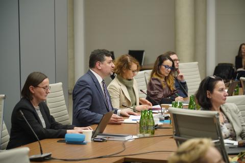 Wypowiadający się Mirosław Wróblewski i cztery inne osoby siedzą u szczytu konferencyjnego stołu w dużej sali konferencyjnej