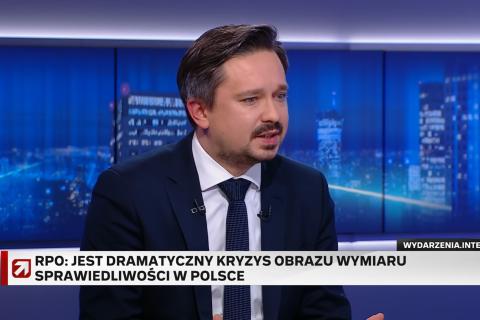 Zrzut ekranu programu telewizyjnego przedstawiający RPO Marcina Wiącka siedzącego w studiu telewizyjnym