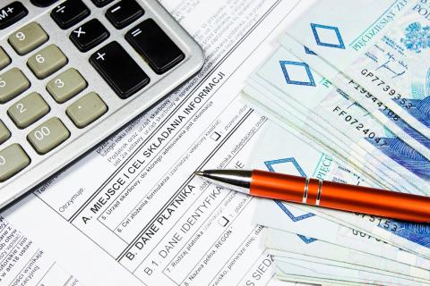 Banknoty, długopis i kalkulator leżące na formularzu do rozliczenia podatku