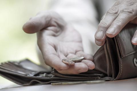 Kilka monet leży na dłoni obok pustego portfela