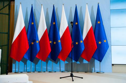 Przygotowany do konferencji prasowej mikrofon, stojący na tle flag Polski i Unii Europejskiej
