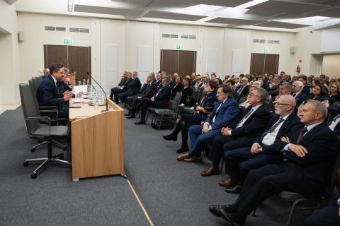 Kilkadziesiąt osób siedzących na dużej sali słucha wystąpienia RPO Marcina Wiącka siedzącego za stołem prezydialnym