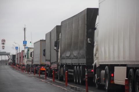 Kolejka kilkudziesięciu samochodów ciężarowych stojących na drodze w kierunku przejścia granicznego