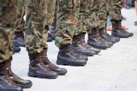 Kadr na nogi stojących w linii osób ubranych w mundury polowe