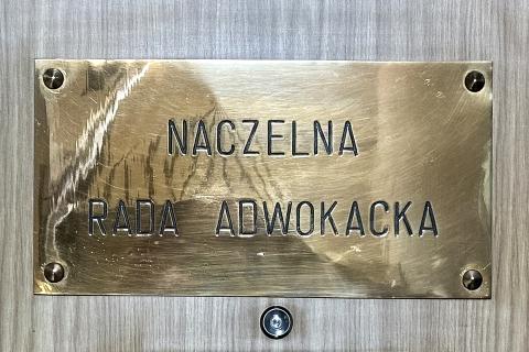 Mosiężna tabliczka z wygrawerowanym napisem "Naczelna Rada Adwokacka" przytwierdzona do drewnianych drzwi
