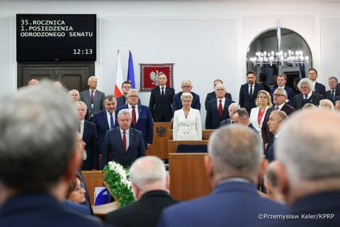Uczestnicy uroczystości, w tym RPO Marcin Wiącek, stoją na baczność w sali obrad Senatu RP.