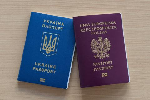dwie książeczki paszportowe w kolorze niebieskim i brązowym leżące obok siebie