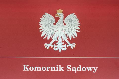 tablica z polskim godłem i napisem komornik sądowy
