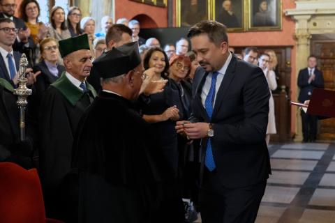 RPO Marcin Wiącek przypina medal prof. Aleksandrowi Lichorowiczowi w zabytkowej auli jagiellońskiej Uniwersytetu Jagiellońskiego w Krakowie