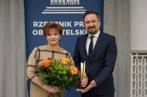 RPO Marcin Wiącek i trzymająca kwiaty oraz statuetkę nagrody Urszula Jaworska pozują do zdjęcia uśmiechając się