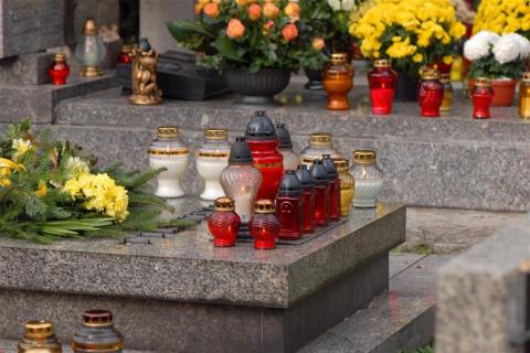 grób na cmentarzu z kwiatami i zniczami