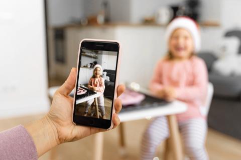 ręka trzyma smartfon którym robi zdjęcie małej dziewczynce 