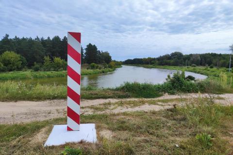 słup w biało-czerwone pasy w tle zakole rzeki 