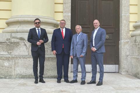 Cztery osoby pozują do wspólnego zdjęcia przed wejściem do zabytkowego budynku
