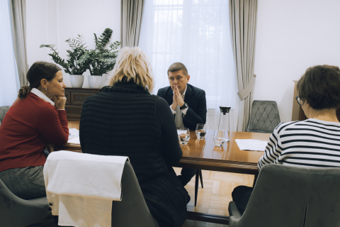 Cztery osoby siedzą przy stole i rozmawiają