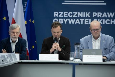 osoby siedzą w sali za stołem