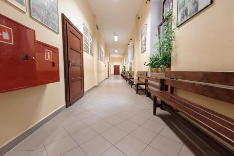 Korytarz z ławkami pod jedna ze ścian w placówce oświatowej