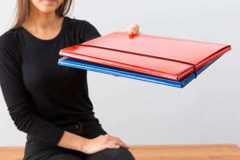 osoba trzyma kilka teczek dokumentów