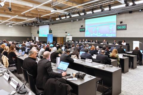 Kilkadziesiąt osób siedzi na dużej sali obrad