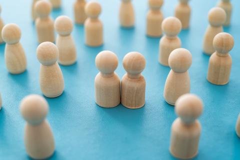 dwa stylizowane ludziki obok siebie na tle innych, rozproszonych