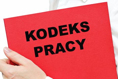 dłoń trzymająca książka z tekstem kodeks pracy 