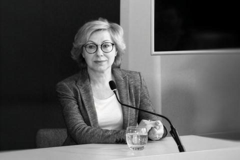 Czarno-białe zdjęcie Jolanty Florek siedzącej przy stole konferencyjnym