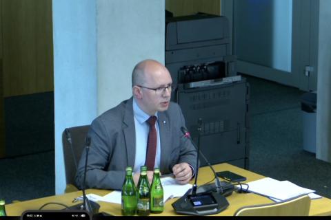 osoba przemawia siedząc w sali 