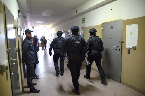 osoby w mundurach idą przez korytarz posczas gdy inne stoją 