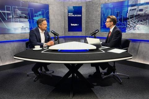 Dwie osoby rozmawiają przy stole w studio telewizyjnym