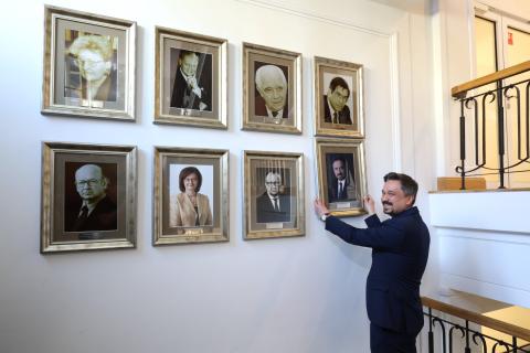 Osoba wiesza na ścianie z portretami nowy portret
