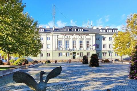 Duży, trzypiętrowy budynek stojący na placu z napisem "Urząd Miasta i Gminy, Starostwo Powiatowe"
