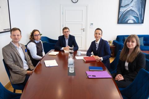 Pięć osób pozuje do wspólnego zdjęcia siedząc przy dużym stole konferencyjnym