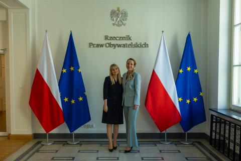 zdjęcie przedstawia dwie pozujące osoby - rpo i rpd - do zdjęcia na tle flag PL i UE