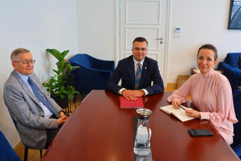 Sylwia Gregorczyk-Abram, Maciej Wróbel i Stanisław Trociuk uśmiechają się siedząc przy stole w gabinecie Rzecznika
