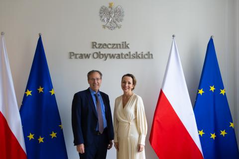 Sylwia Gregorczyk-Abram i Miguel Berger pozują do zdjęcia na tle flag Polski i Unii Europejskiej oraz napisu "Rzecznik Praw Obywatelskich"