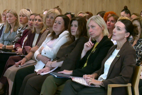 Kilkadziesiąt osób siedzi na sali konferencyjnej i przysłuchuje się czyjemuś wystąpieniu